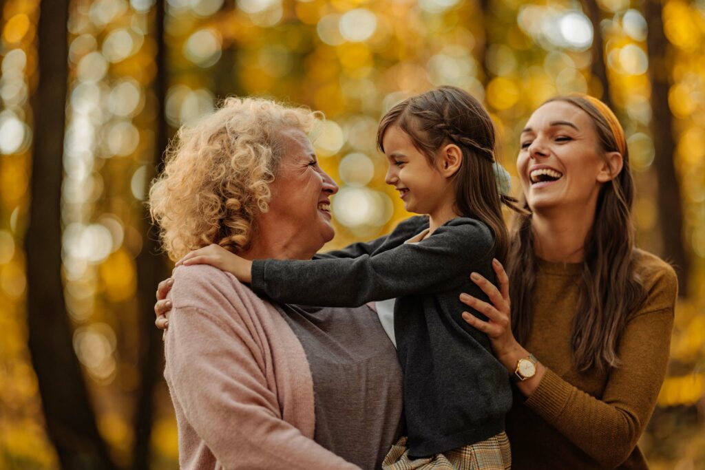 A grandmother, daughter and grand daughter laugh together.